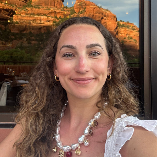 Woman with a scenic background of red rock formations and a clear blue sky.